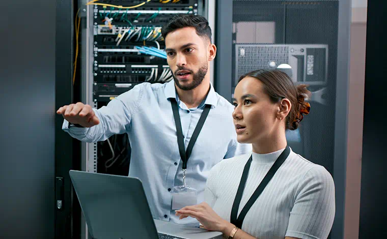 Two people using a laptop in a data center