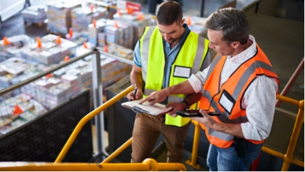 Two people looking at a clipboard in a warehouse