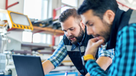 Two people using a laptop in a warehouse