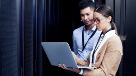 Two people using a laptop in a warehouse