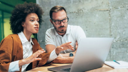 Two people using a laptop at a table