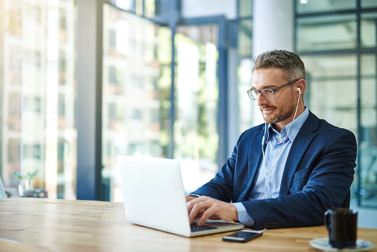 Person wearing ear buds working on a laptop