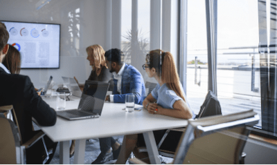 5 people are sitting in an office for a meeting